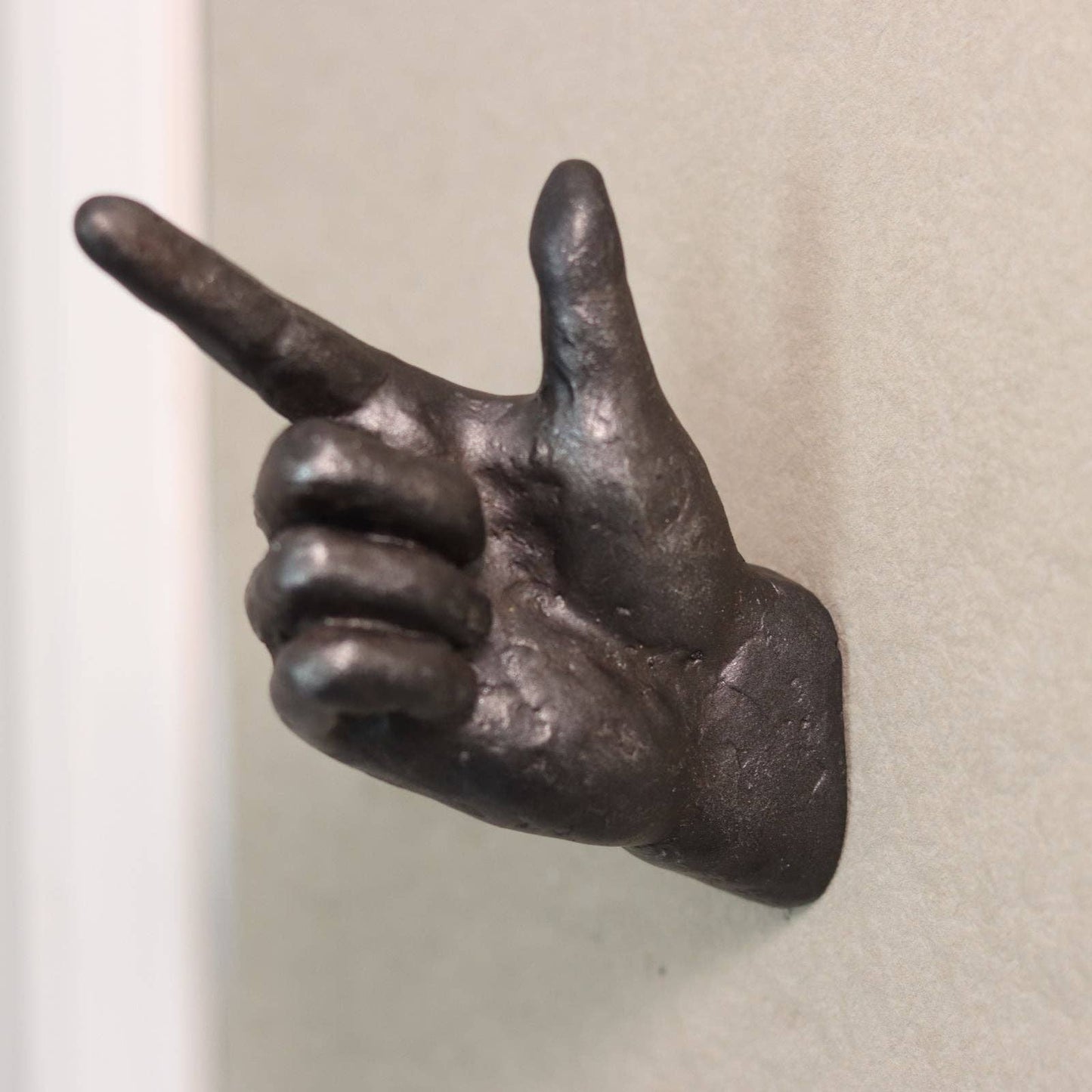 Bronze hand sculpture making a peace sign on a plain background