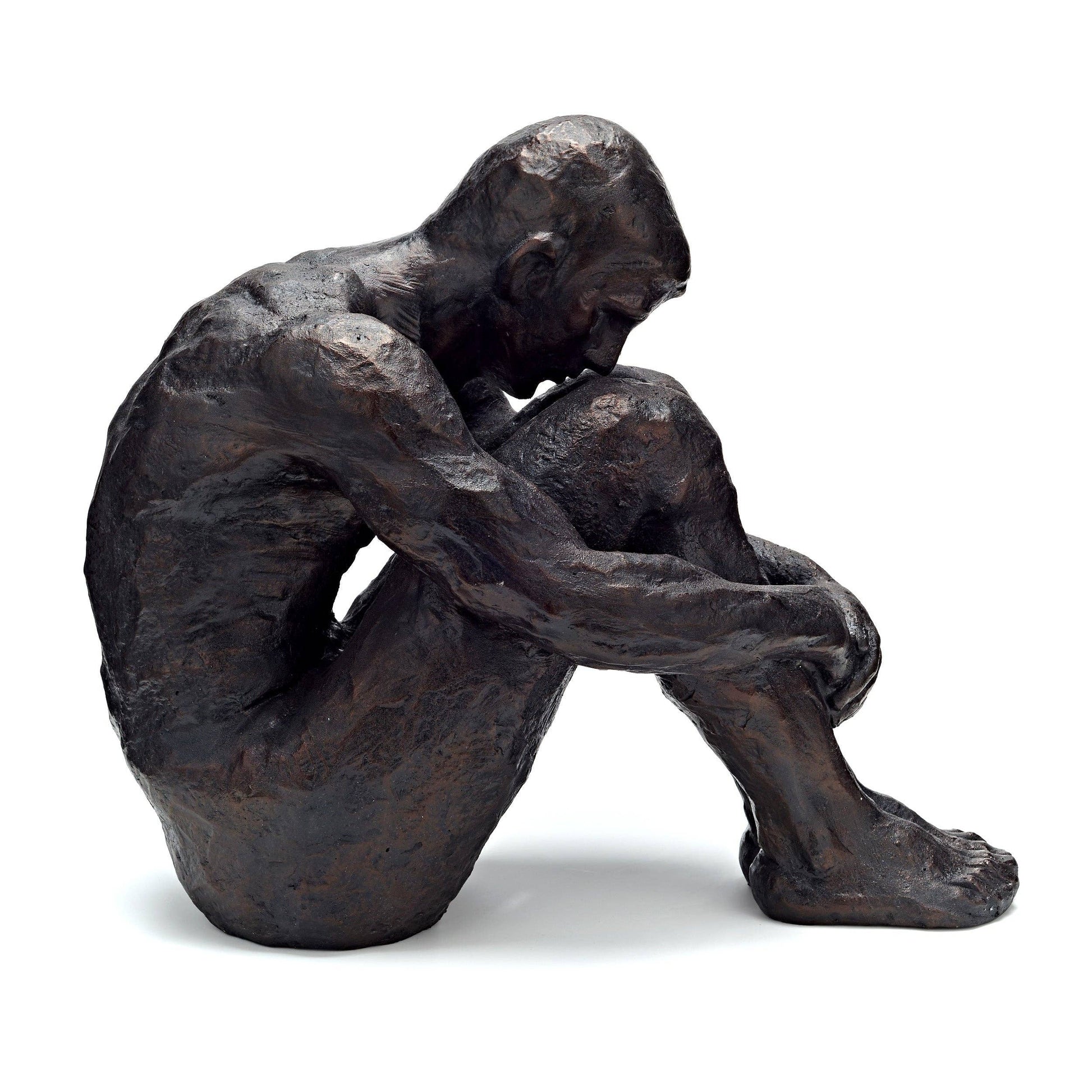 Bronze sculpture of a seated figure with hands clasped, on a white background