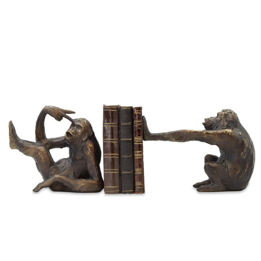 Bronze monkey bookends holding a book on a white background