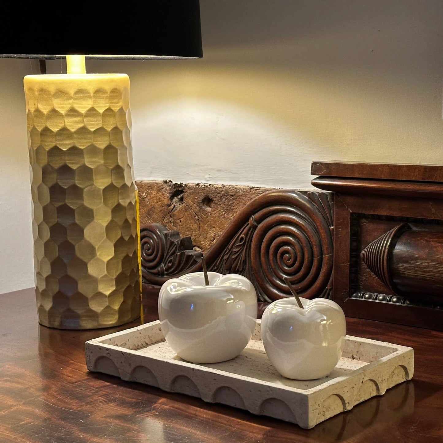 Decorative apples on a stone tray with a textured lamp in the background