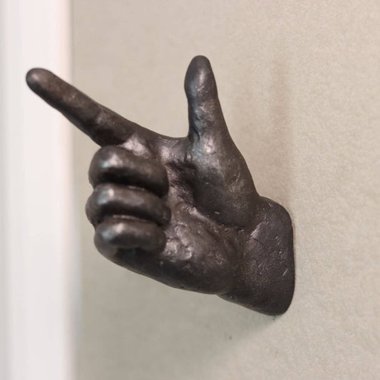 Bronze hand sculpture making a peace sign on a plain background