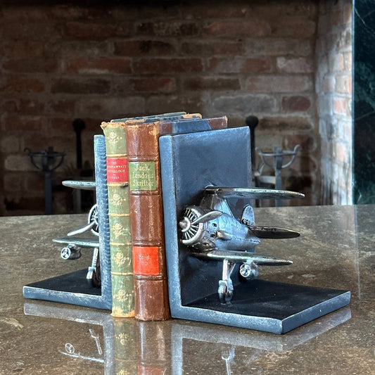 Bookends shaped like airplanes on a table with a brick wall background