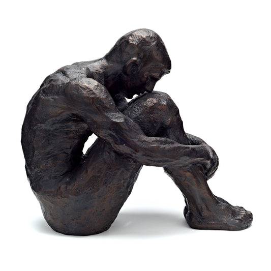 Bronze sculpture of a seated figure with hands clasped, on a white background