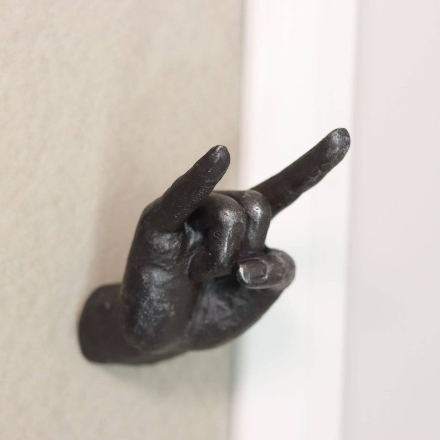 Metallic hand-shaped door knocker on a neutral background
