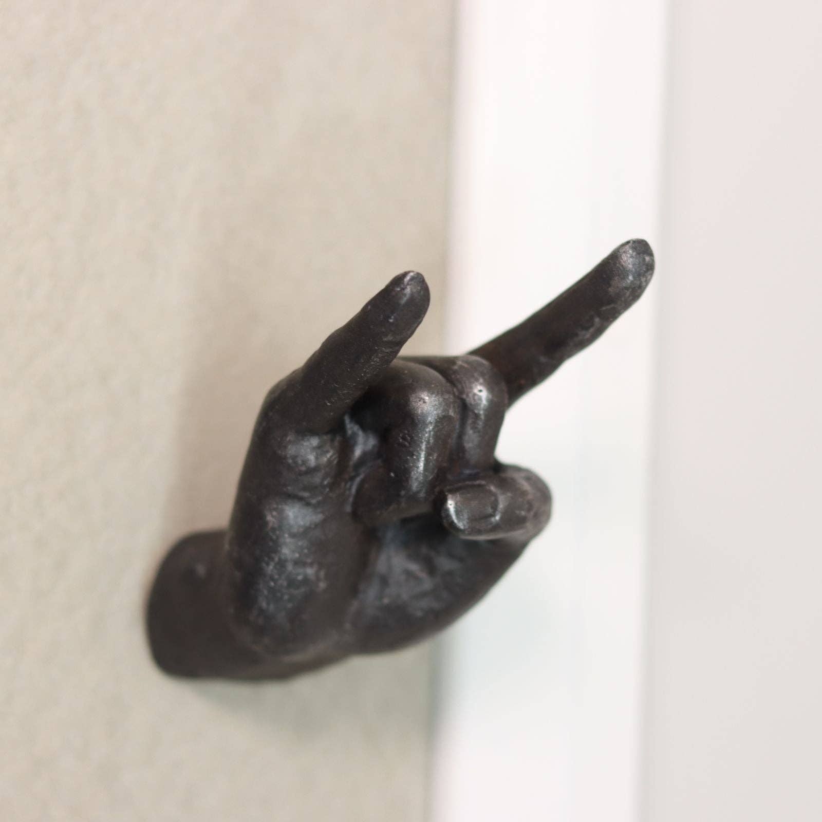 Metallic hand-shaped door knocker on a neutral background